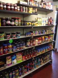 Supermarket shelves stocked with jars, bottles, and tins of various food products.